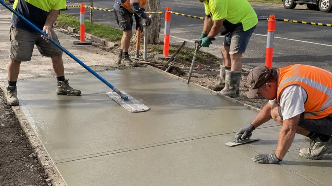 Concrete crew floating and troweling a freshly poured driveway slab