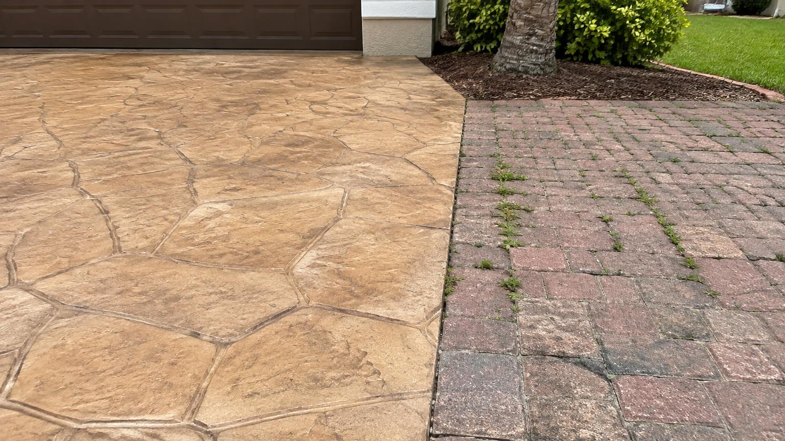 Stamped concrete driveway next to weedy brick pavers