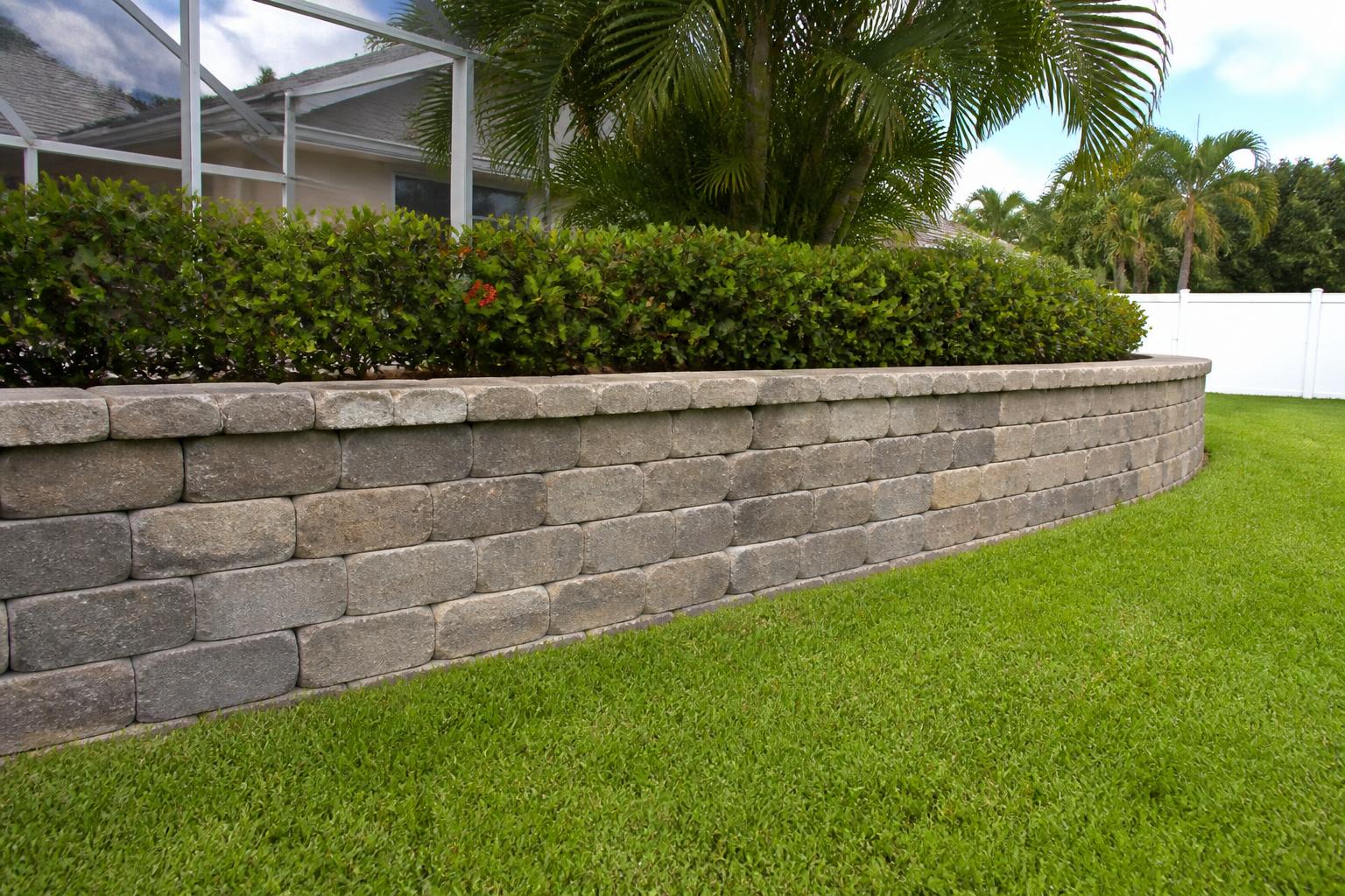 Capped block retaining wall along a backyard planting bed in Chiefland, Florida